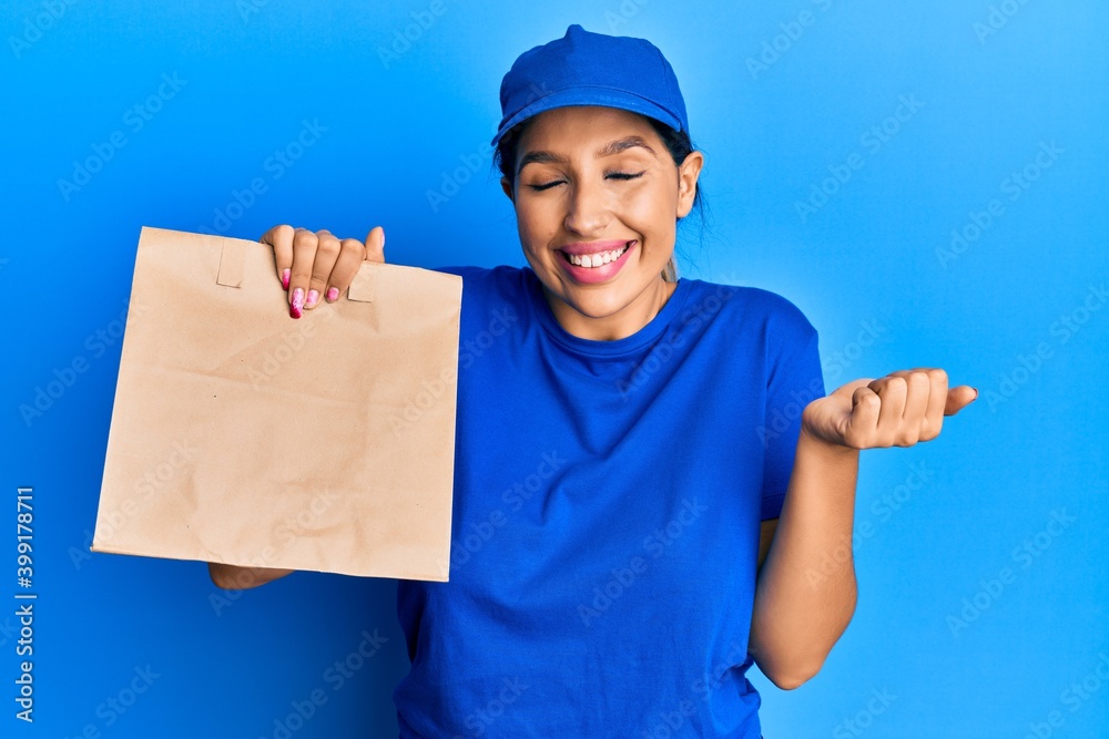 Beautiful brunette woman holding take away paper bag screaming proud, celebrating victory and success very excited with raised arm Beautiful brunette woman holding take away paper bag screaming proud, celebrating victory and success very excited with raised arm