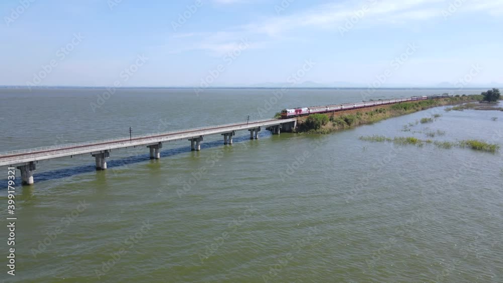 Aerial view of Thailand Excursion train run slowly for parking on the floating railway bridge with blue sky in the lake of Aerial view of Thailand Excursion train run slowly for parking on the floating railway bridge with blue sky in the lake of