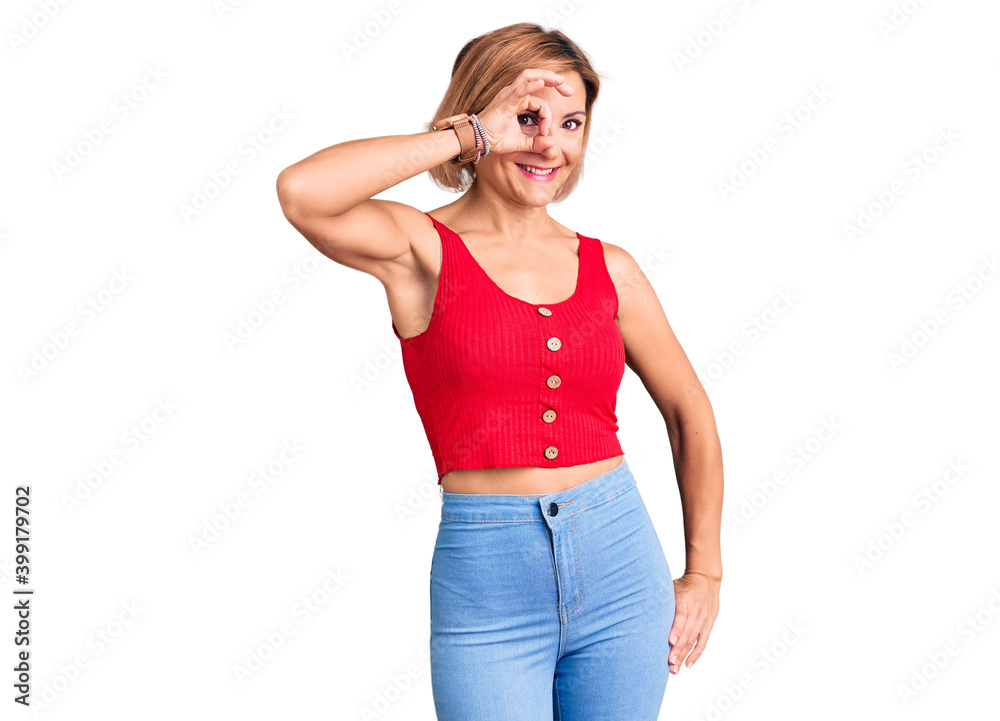 Young blonde woman wearing casual clothes smiling happy doing ok sign with hand on eye looking through fingers Young blonde woman wearing casual clothes smiling happy doing ok sign with hand on eye looking through fingers