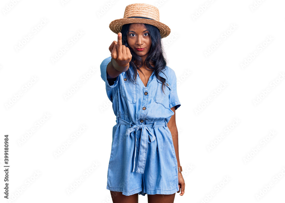 Young indian girl wearing summer hat showing middle finger, impolite and rude fuck off expression Young indian girl wearing summer hat showing middle finger, impolite and rude fuck off expression