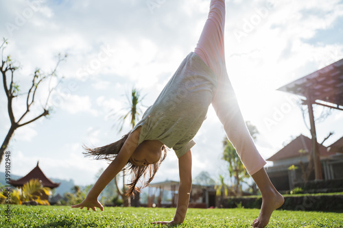 Fotografi Little girl enjoyed playing somersault in the garden at the sunny day