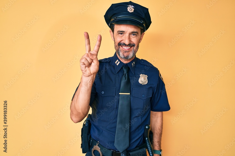 Middle age hispanic man wearing police uniform showing and pointing up with fingers number two while smiling confident and happy. Middle age hispanic man wearing police uniform showing and pointing up with fingers number two while smiling confident and happy.