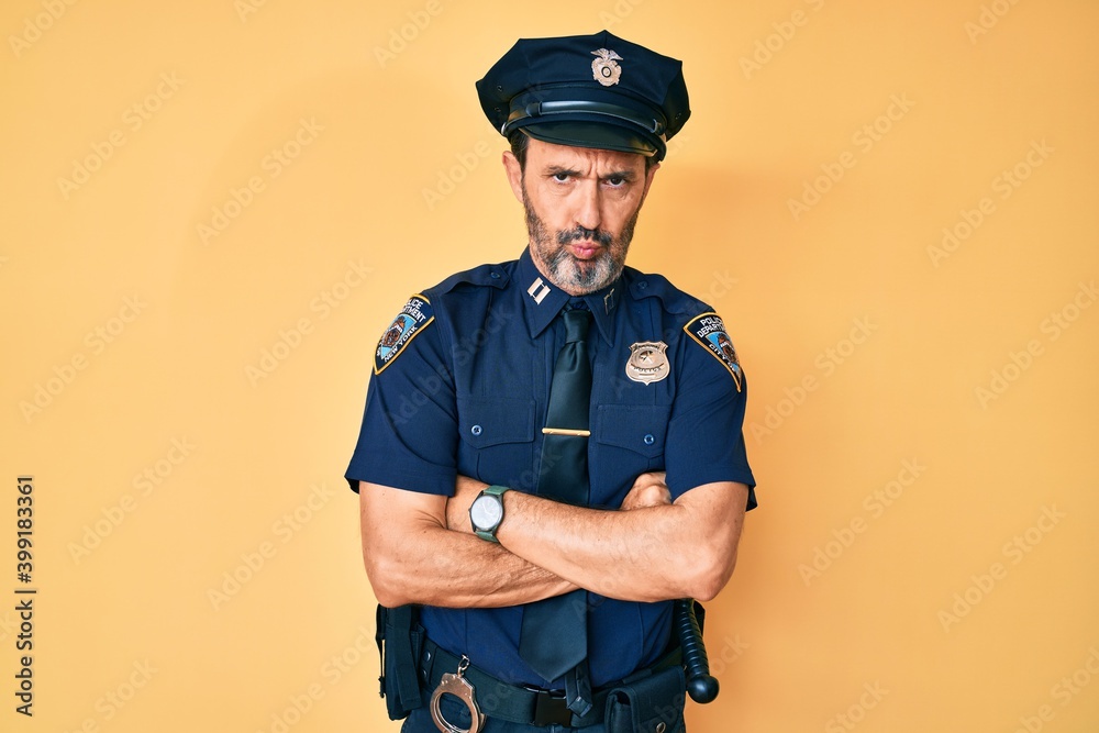Middle age hispanic man wearing police uniform skeptic and nervous, disapproving expression on face with crossed arms. negative person. Middle age hispanic man wearing police uniform skeptic and nervous, disapproving expression on face with crossed arms. negative person.