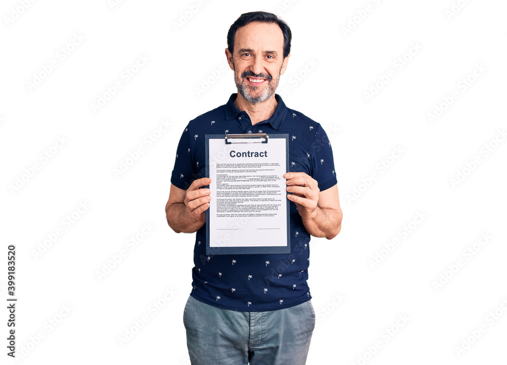 Middle age handsome man holding clipboard with contract document looking positive and happy standing and smiling with a confident smile showing teeth Middle age handsome man holding clipboard with contract document looking positive and happy standing and smiling with a confident smile showing teeth