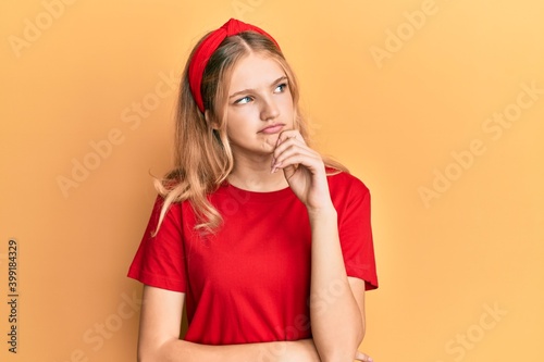 Beautiful young caucasian girl wearing casual red t shirt thinking concentrated about doubt with finger on chin and looking up wondering