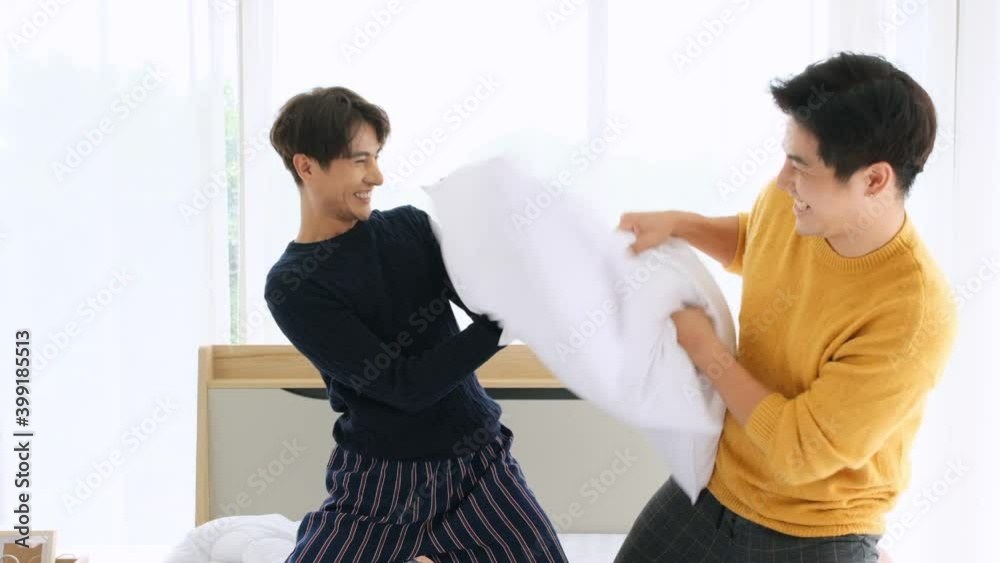 Two lgbt couple fighting with pillows happily in the bedroom,slow motion shot.lgbt and gay couple concept.
