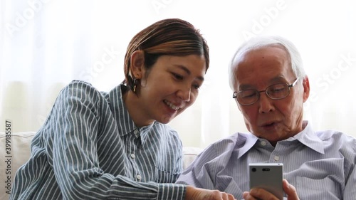 スマートフォンを見ながら話す日本人シニア男性と娘