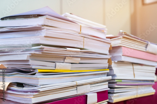 Pile of books and documents report papers waiting be managed on desk in busy office. Concept of workload in business finacial paperwork information planing