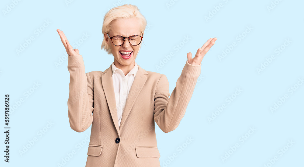 Young blonde woman wearing business clothes and glasses celebrating mad and crazy for success with arms raised and closed eyes screaming excited. winner concept