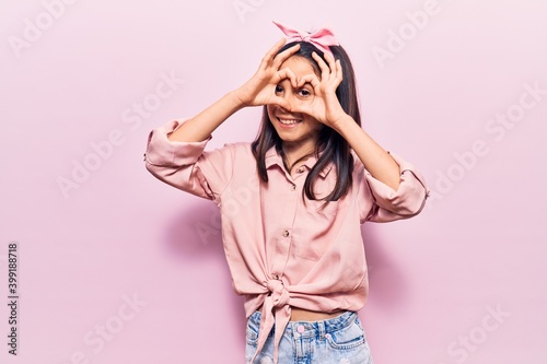 Beautiful child girl wearing casual clothes doing heart shape with hand and fingers smiling looking through sign