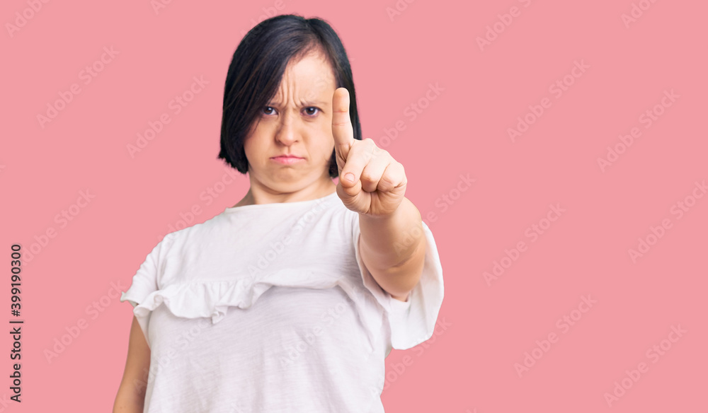 Brunette woman with down syndrome wearing casual white tshirt pointing with finger up and angry expression, showing no gesture Brunette woman with down syndrome wearing casual white tshirt pointing with finger up and angry expression, showing no gesture