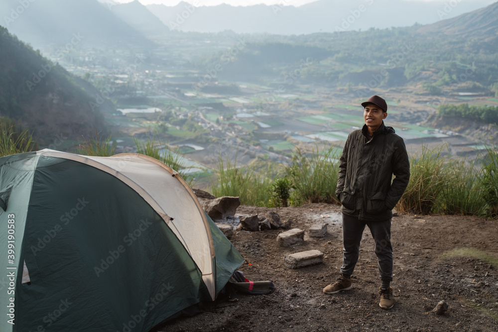 Portrait adventurous man camping captures the moment. Beautiful mountain scenery in the morning