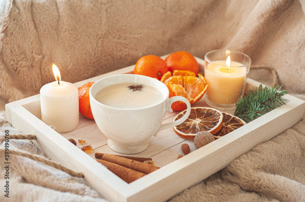 A wooden tray with tea, tangerines, nuts and spices on a beige plaid. Winter breakfast. The concept of hygge. A wooden tray with tea, tangerines, nuts and spices on a beige plaid. Winter breakfast. The concept of hygge.
