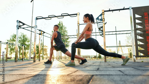 Fototapeta Naklejka Na Ścianę i Meble -  Young man and girl doing lunges exercise during workout