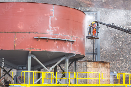 Foto The sandblaster is sandblasting (abrasive blasting) t steel storage tank with a hiab crane in the construction site