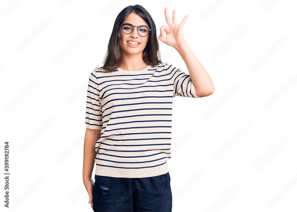 Brunette teenager girl wearing casual clothes and glasses smiling positive doing ok sign with hand and fingers. successful expression. Brunette teenager girl wearing casual clothes and glasses smiling positive doing ok sign with hand and fingers. successful expression.