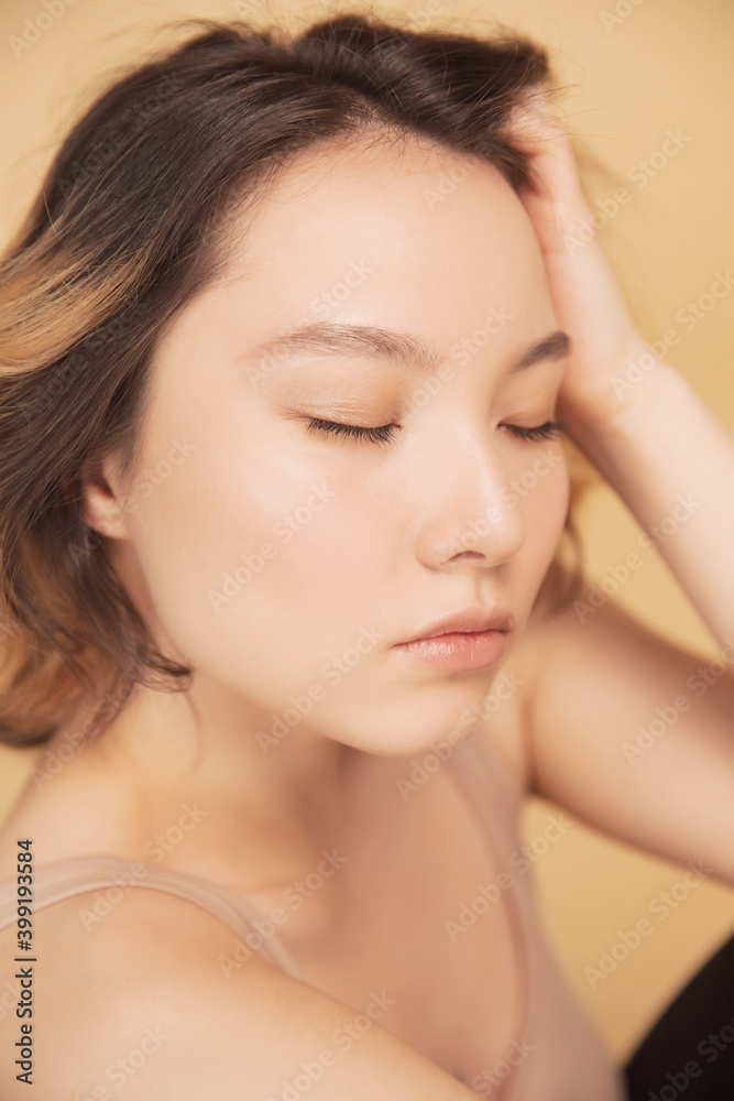 Profile young girl of Asian appearance with wavy streaked hair on beige background. Concept beauty and fashion of face and body skin