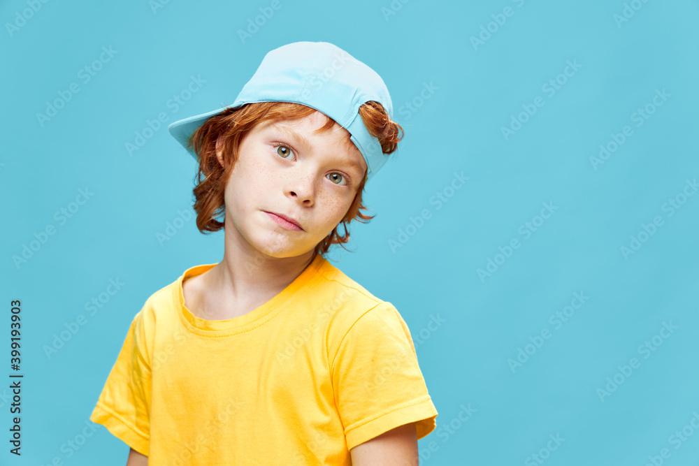 Red-haired boy in a blue cap on his head yellow t-shirt fashionable clothes studio Red-haired boy in a blue cap on his head yellow t-shirt fashionable clothes studio