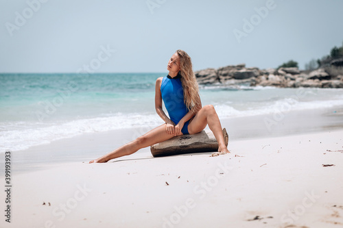 Wallpaper Mural Young pretty blonde woman in a blue swimming suit posing on a beach against the sea background. Summer vacation concept Torontodigital.ca