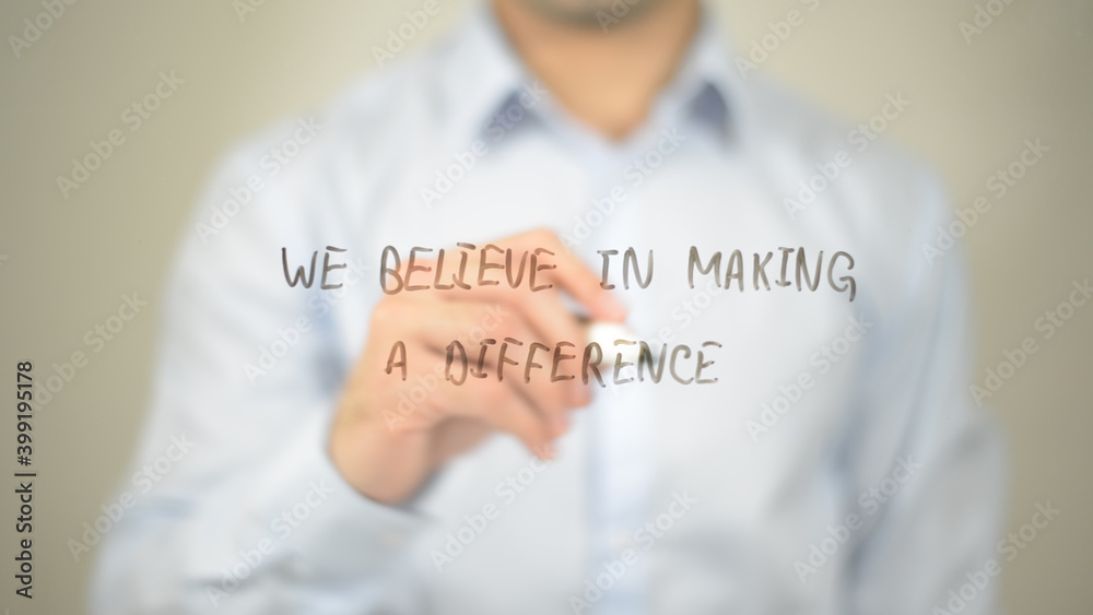 We Believe In Making A Difference , man writing on transparent screen We Believe In Making A Difference , man writing on transparent screen
