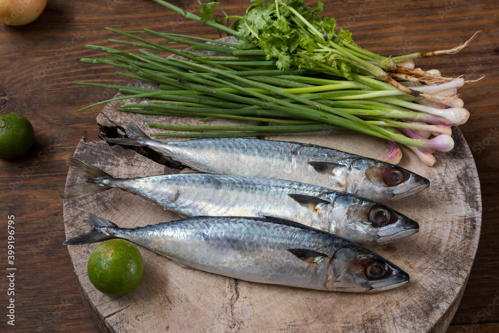 Three Saba Mackerel and Thai cooking ingredients on wooden board and table. Three Saba Mackerel and Thai cooking ingredients on wooden board and table.