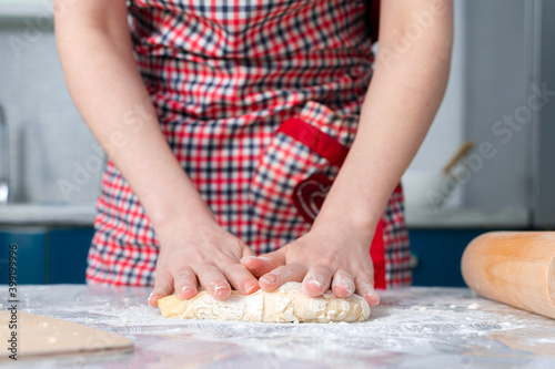 A woman in the apron knead the dough. Close up. The concept of a home-cooked meal