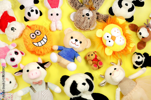 Many stuffed toys on yellow background, top view. 
