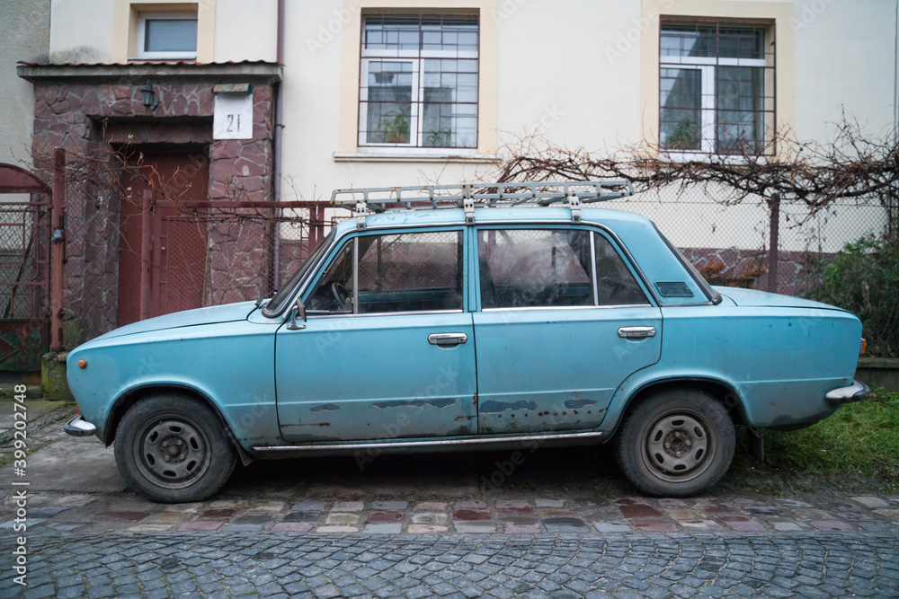 An old blue car near house number 21. Old rusty USSR car. 