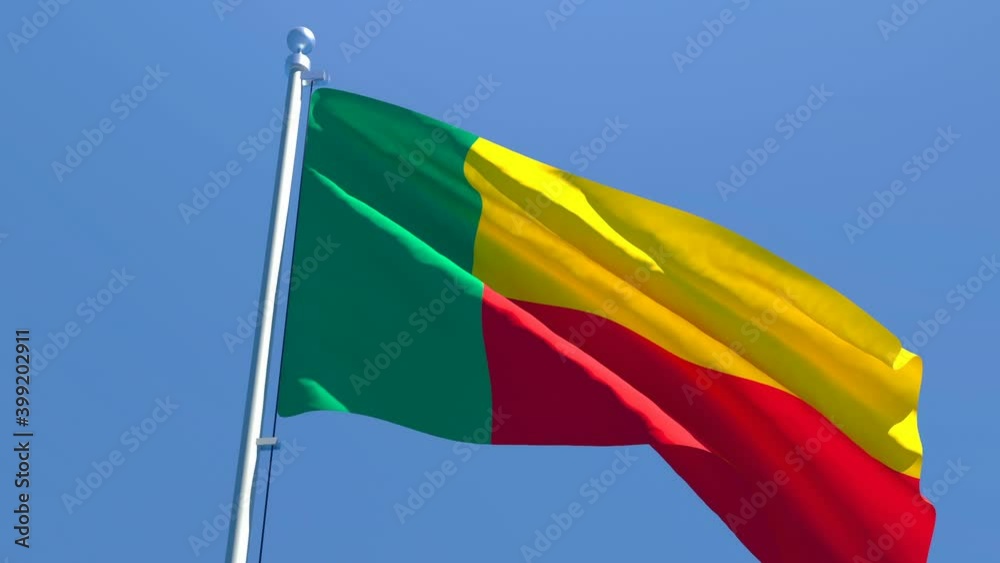 The national flag of Benin is flying in the wind against a blue sky The national flag of Benin is flying in the wind against a blue sky