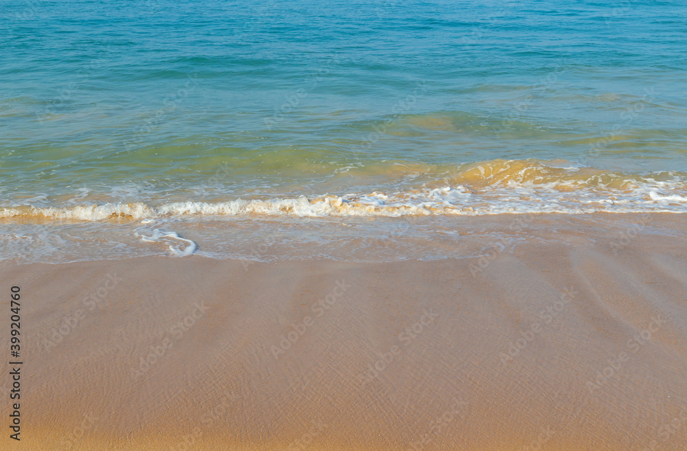 Breaking sea wave on a sandy beach background