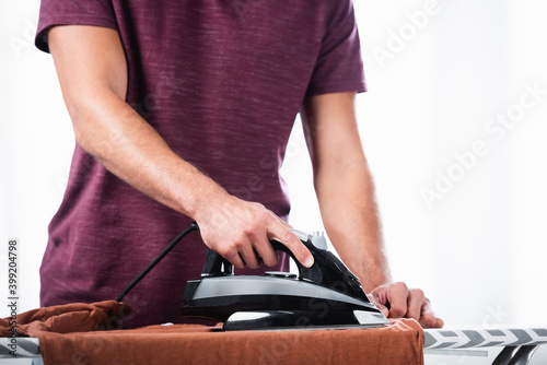 Cropped view of man ironing clothes on board at home