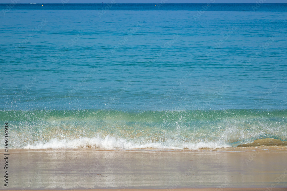 Breaking sea wave on a sandy beach background