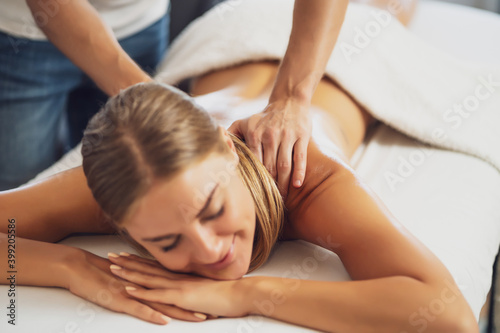 Professional masseur doing therapeutic massage. Woman enjoying massage in her home. Young woman getting relaxing body massage.
