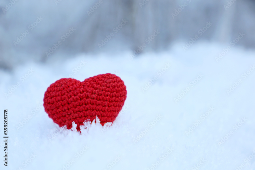 Fototapeta premium Red knitted heart on a snow in winter forest. Background for Christmas holiday, Valentine's card