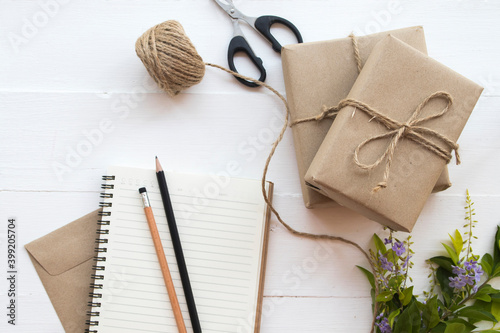 notebook with box package prepare send to customer by post office arrangement flat lay style on background white wooden