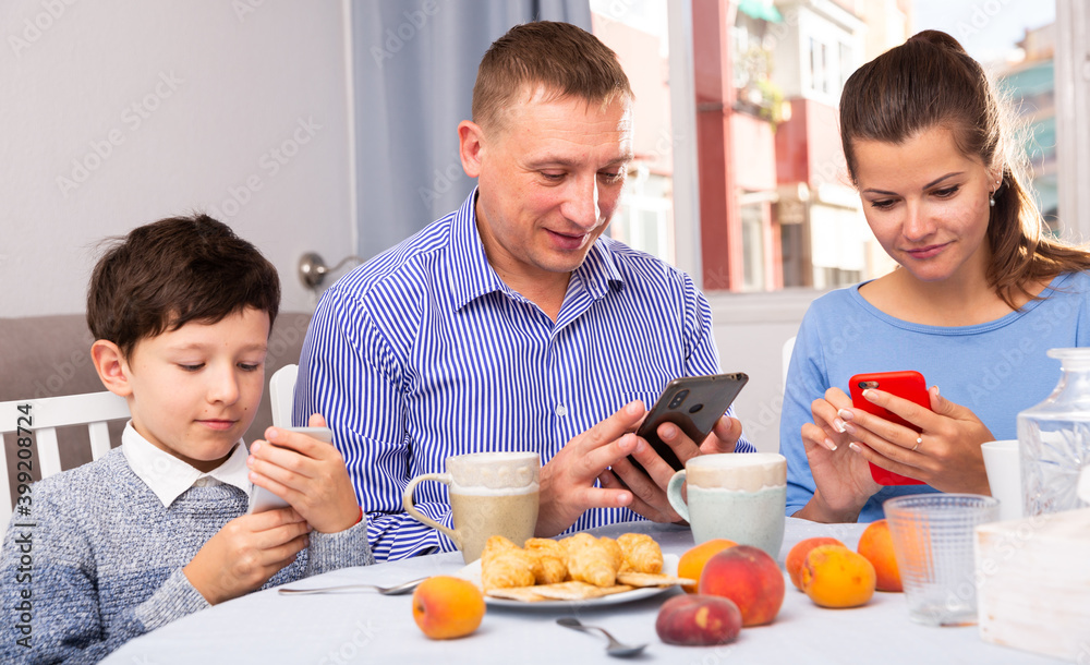 Parents and teen son using phones at kitchen. High quality photo
