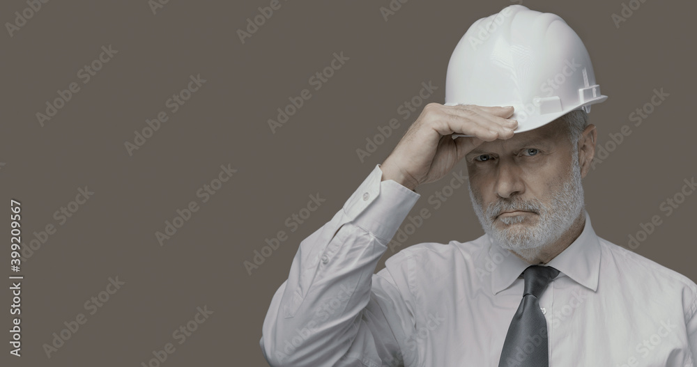 Confident businessman and engineer posing with a safety helmet