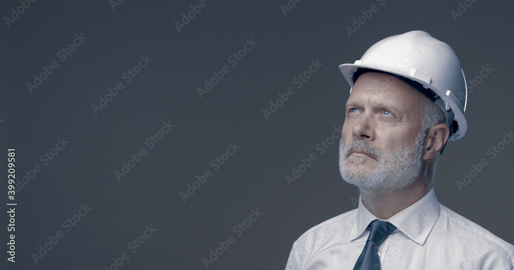 Confident businessman and engineer posing with a safety helmet