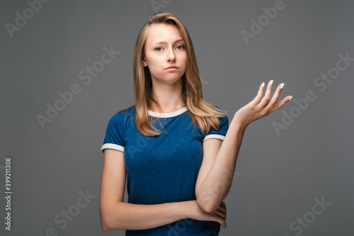 Studio shot of frustrated female is gesturing with raised palm, frowning, being displeased and confused
