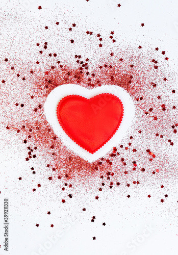 Red confetti glitter in shape of heart on white festive background, copy space, valentines day festive card
