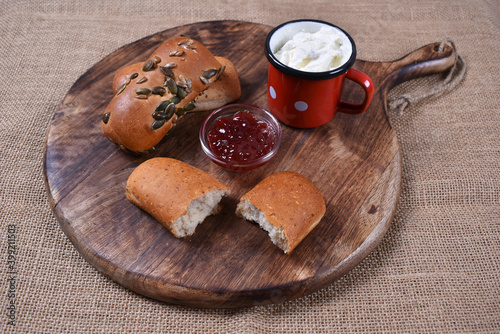 Pastry breakfast with jam and cheese on wooden background with burlap
