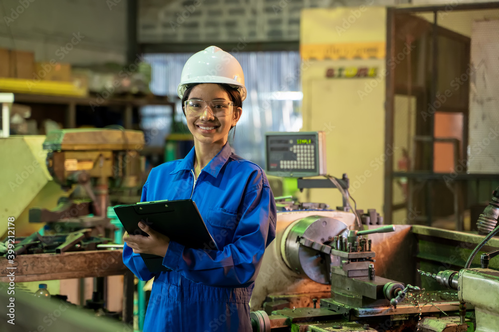 Female industrial worker in protective uniform working and checking machine in a large industrial factory. Female industrial worker in protective uniform working and checking machine in a large industrial factory.