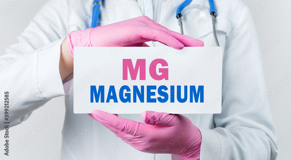Cropped view of female doctor in a white coat and pink sterile gloves holding a card with word MAGNESIUM Cropped view of female doctor in a white coat and pink sterile gloves holding a card with word MAGNESIUM