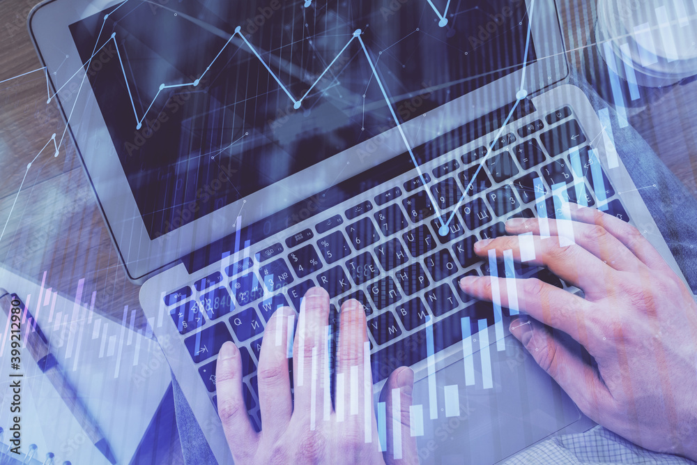 Double exposure of man's hands typing over computer keyboard and forex graph hologram drawing. Top view. Financial markets concept.