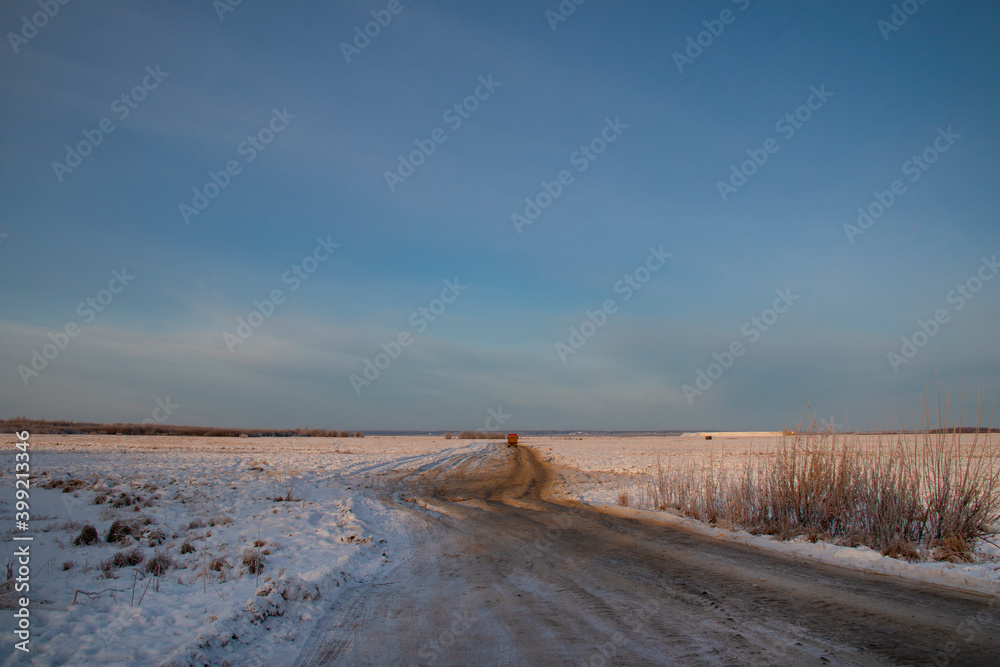 Winter roads of the North. Dirt frozen uneven road stretches through many kilometers of snow.