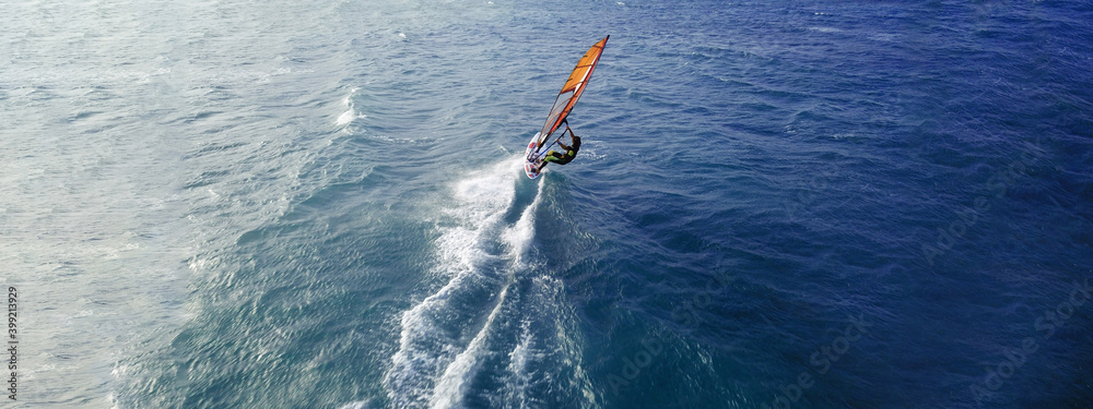 Aerial drone ultra wide top view photo of fit man practising wind surfing in Mediterranean bay with crystal clear emerald sea