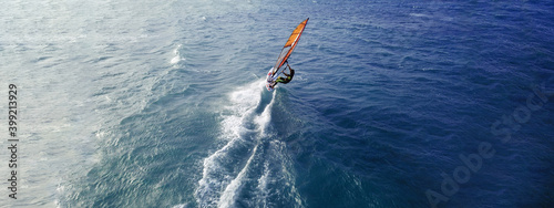 Aerial drone ultra wide top view photo of fit man practising wind surfing in Mediterranean bay with crystal clear emerald sea © aerial-drone