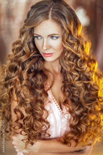 Close up portrait of young beautiful woman with luxurious curly long hair.