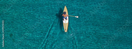 Aerial drone ultra wide photo of fit man practising Stand Up Paddle or SUP in tropical exotic bay with emerald sea