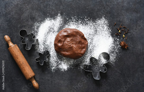 Flour and dough with a rolling pin on the kitchen table. New Year's pastries. Layout of ingredients for making a gingerbread man.